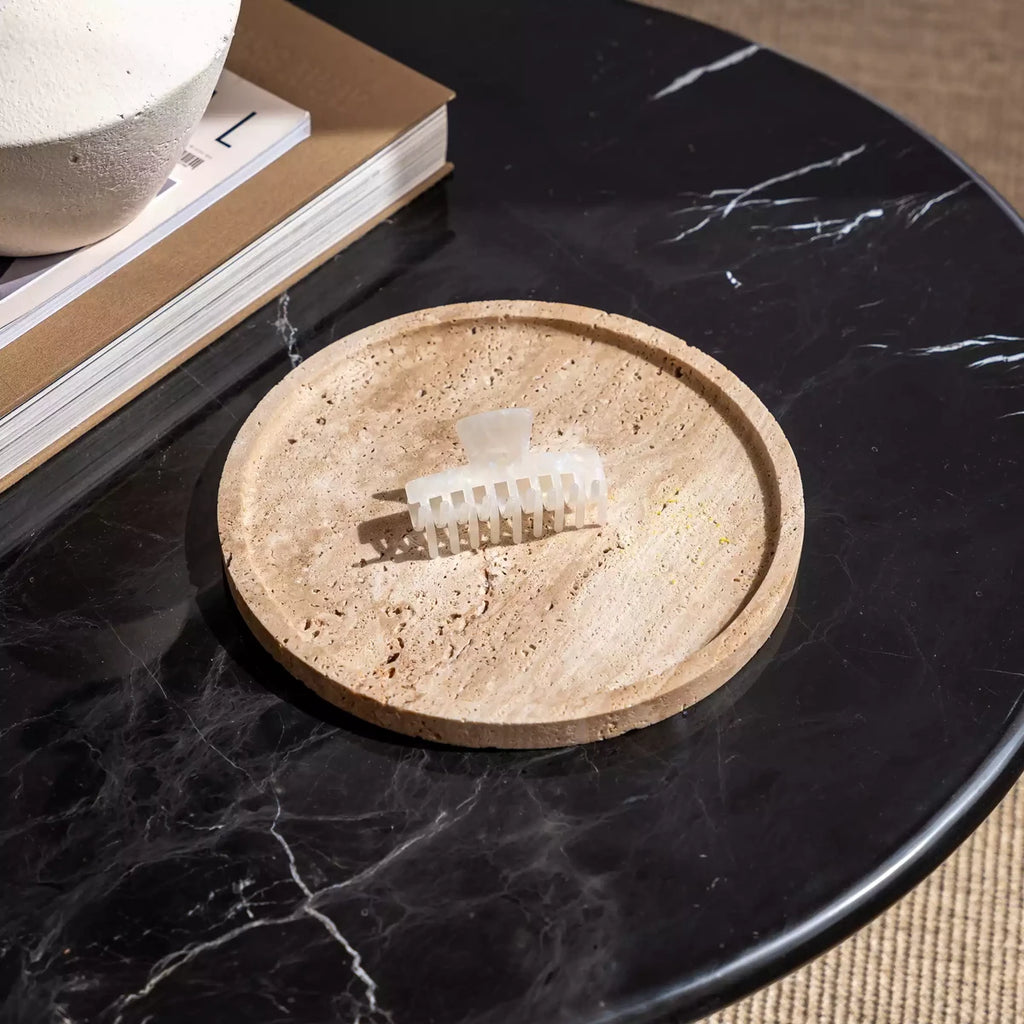 Top view of a pearlescent beige claw hair clip on a round tray