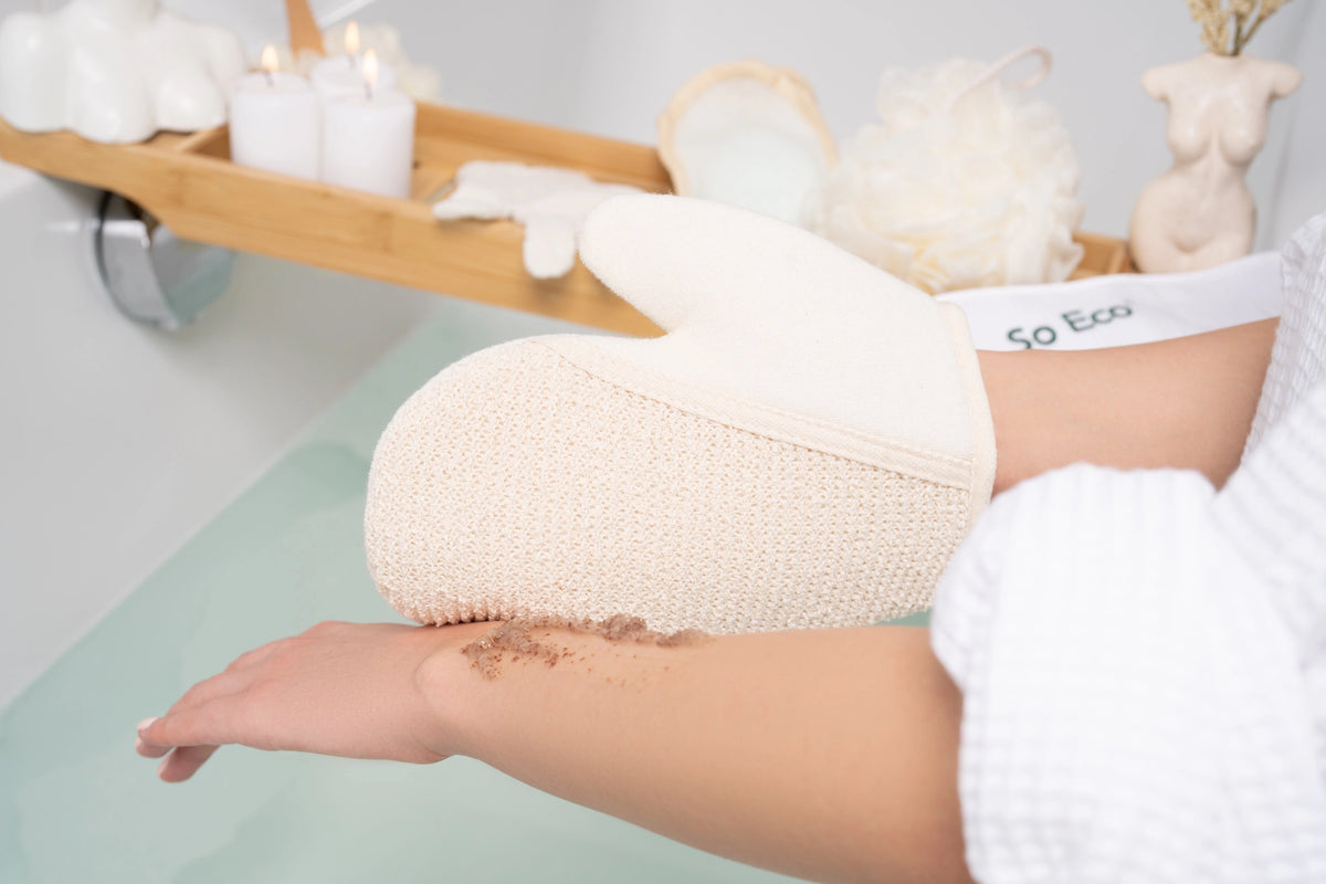 Strukturerad exfolieringshandske använd på armen under en bad- och kroppsvårdsrutin