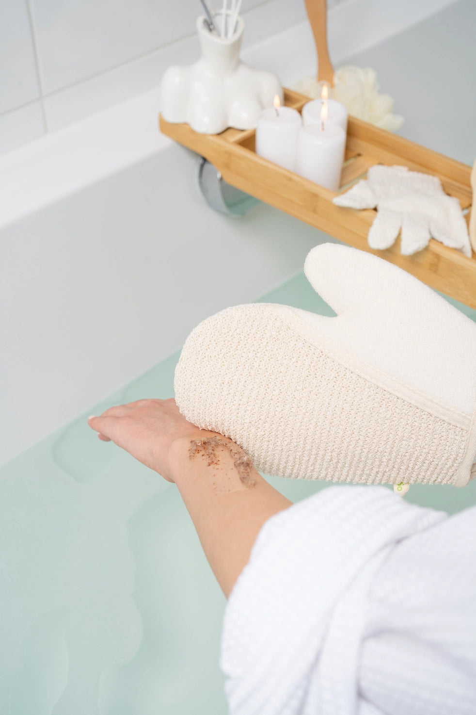 Dubbelsidig exfolieringshandske som varsamt masserar kroppsskrubb över armen