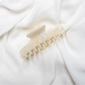 Pearlescent beige claw hair clip on white satin fabric