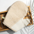 Strukturerad sida av den naturbeige exfolieringshandsken för kroppen på en bambubricka